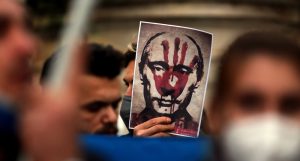 פניו של פוטין על כרזה במהלך התכנסות של מפגינים אוקראינים נגד המלחמה | צילום : Shutterstock