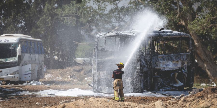 לוחם אש מכבה אוטובוס בוער שספג פגיעה מטיל בחניון אוטובוסים, סמוך להרצליה. 17 ביוני | צילום: חיים גולדברג, פלאש 90